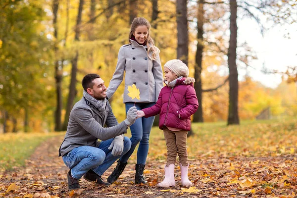 Familia feliz con hoja de arce en el parque de otoño —  Fotos de Stock