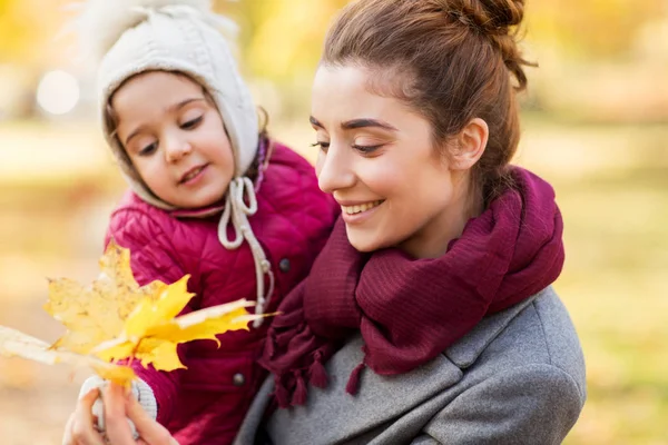 Anne ve küçük kızı sonbahar yaprakları ile — Stok fotoğraf