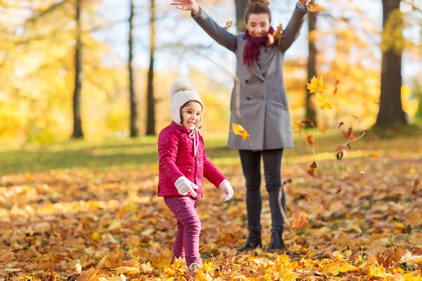 Lycklig familj spelar med hösten lämnar på park — Stockfoto