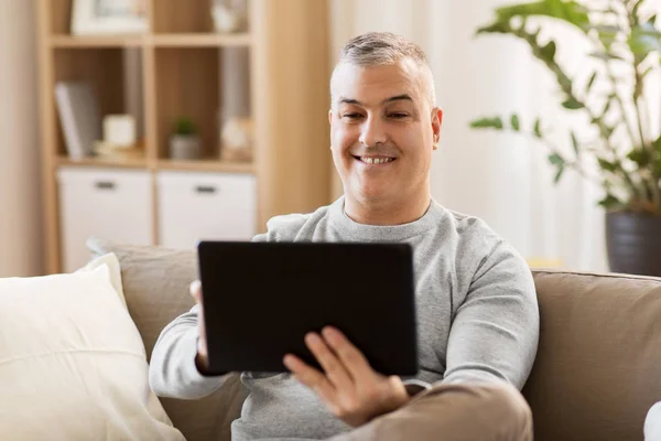 Człowiek z komputera typu tablet, siedząc na kanapie w domu — Zdjęcie stockowe