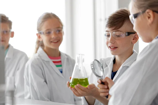 Niños con frasco y lupa en la clase de química — Foto de Stock