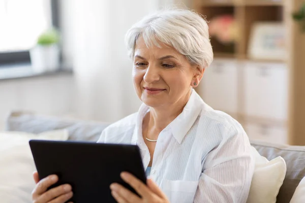 Felice donna anziana con tablet pc a casa — Foto Stock