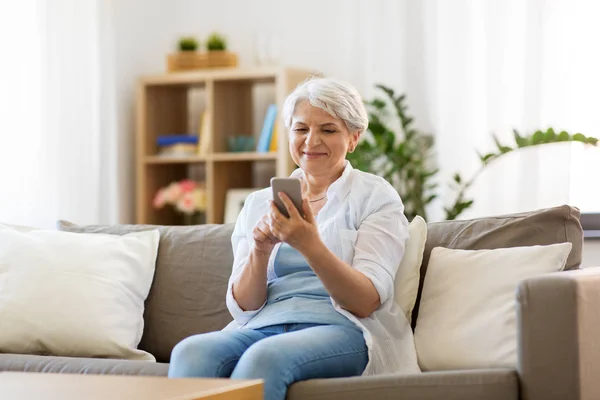 Evde akıllı telefonu olan mutlu bir son sınıf kadını. — Stok fotoğraf