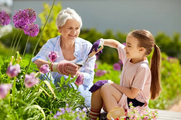 Abuela y niña plantando flores en el jardín — Foto de Stock