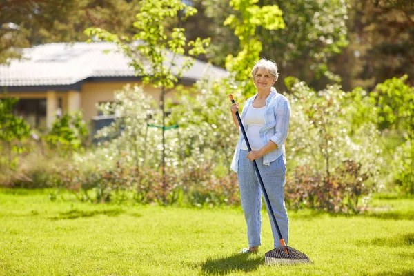 Femme âgée avec râteau de pelouse travaillant au jardin — Photo