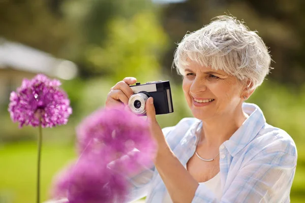 Senior femme avec caméra photographiant des fleurs — Photo