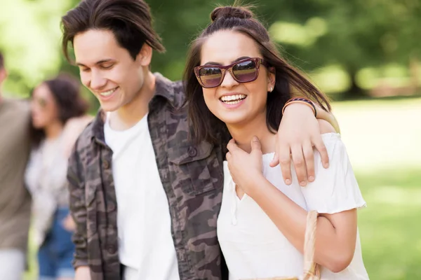 Feliz pareja con amigos en el parque de verano — Foto de Stock