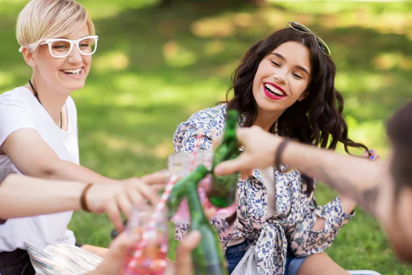 Glada vänner spottar drycker på sommaren park — Stockfoto