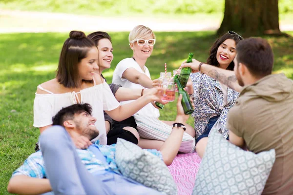 Friends clinking drinks at picnic in summer park — Stock Photo, Image