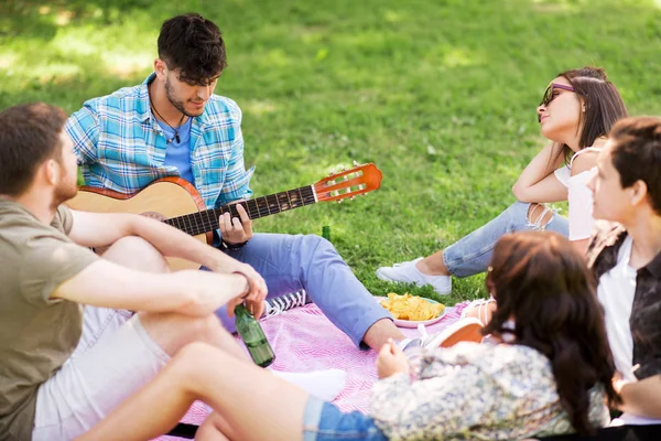 Amigos tocando guitarra no piquenique no parque de verão — Fotografia de Stock