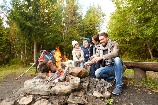Glückliche Familie grillt Marshmallow am Lagerfeuer Stockbild