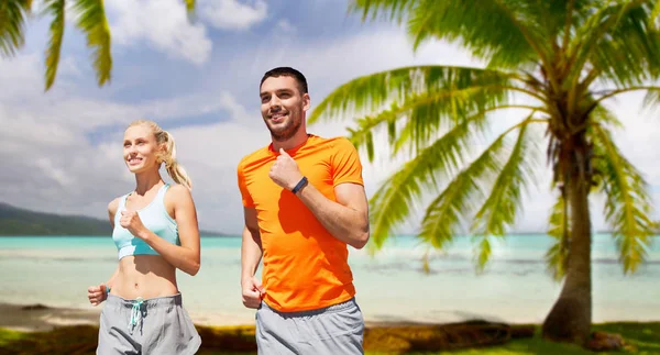 Sorridente coppia che corre sulla spiaggia tropicale — Foto Stock