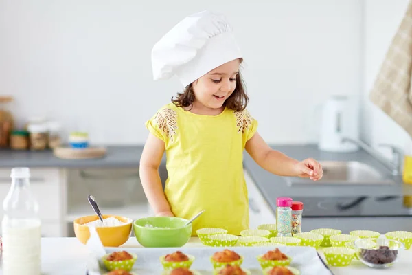 Klein meisje in koks toque bakken muffins thuis — Stockfoto