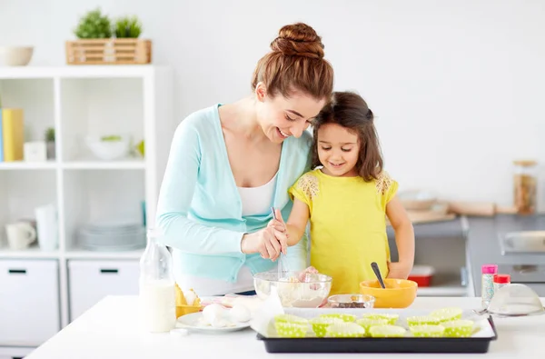 Mãe feliz e filha assar muffins em casa — Fotografia de Stock