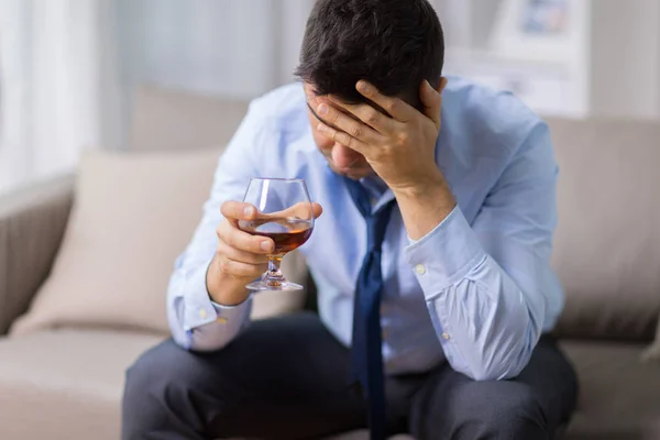 П'яний чоловік зі склянкою алкоголю вдома — стокове фото