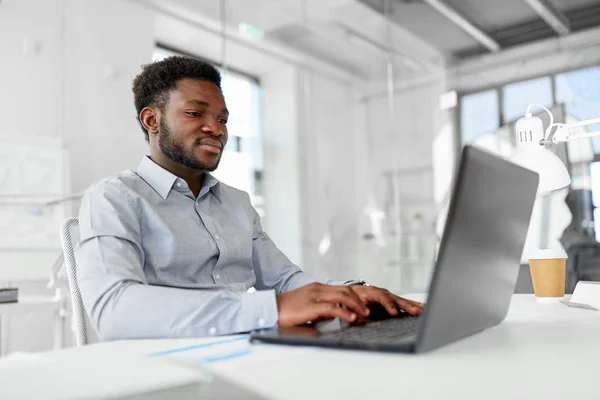 Empresário afro-americano com laptop no escritório — Fotografia de Stock