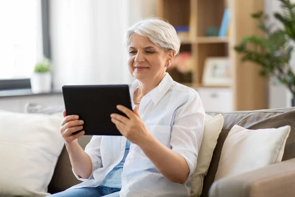 Felice donna anziana con tablet pc a casa — Foto Stock