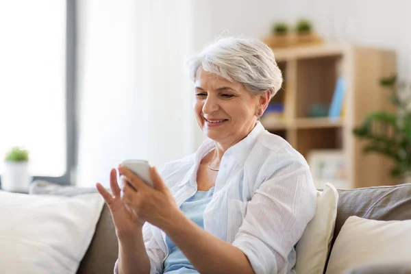 Glückliche Seniorin mit Smartphone zu Hause — Stockfoto