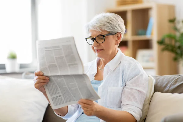 Senior woman reading newspaper at home — Stock Photo, Image