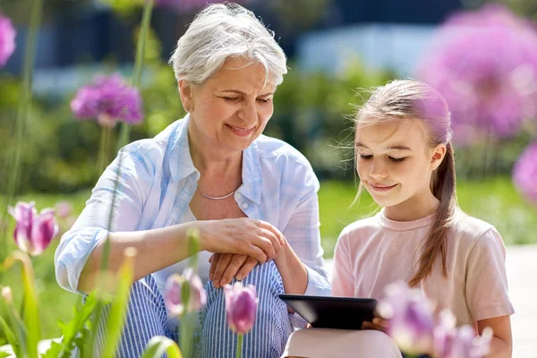 Babcia i dziewczyna z komputera typu tablet w ogrodzie — Zdjęcie stockowe