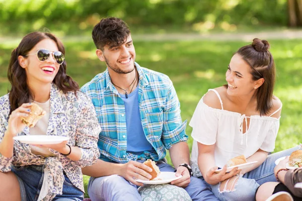 Happy vrienden eten broodjes bij zomerpicknick — Stockfoto