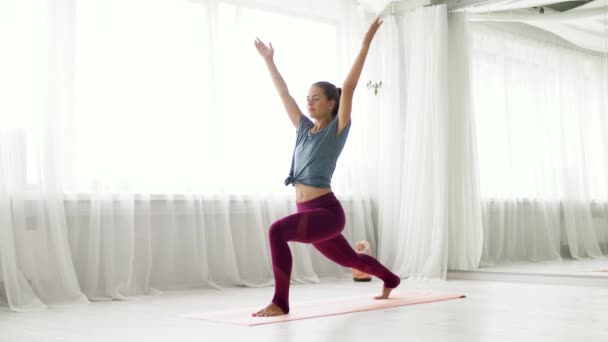 Женщина делает упражнения высокого выпада в студии йоги — стоковое видео