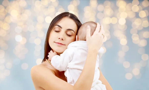 Mutter mit Baby über festlichem Lichterhintergrund — Stockfoto