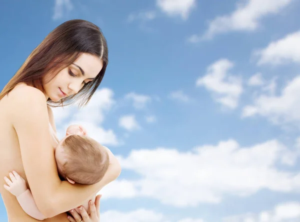 Mother breast feeding baby over sky background — Stock Photo, Image