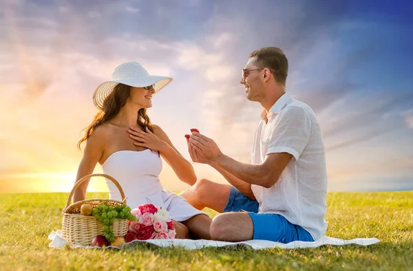 Lachende paar met kleine rode geschenkdoos op picnic — Stockfoto