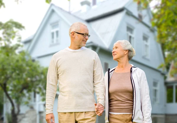 Glückliches Seniorenpaar hält Hand über Haus — Stockfoto