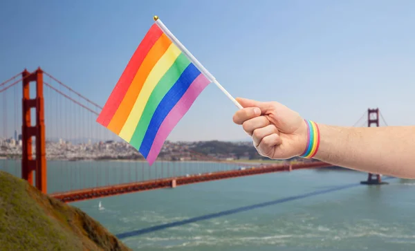 Hand with gay pride rainbow flag and wristband — Stock Photo, Image