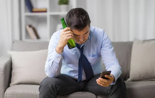 Homem com smartphone e garrafa de cerveja em casa — Fotografia de Stock