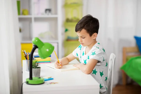 Menino escrevendo para notebook em casa — Fotografia de Stock