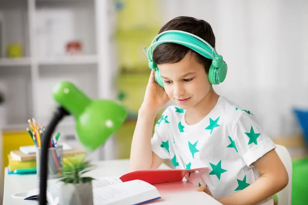 Student pojke i hörlurar läser bok hemma — Stockfoto