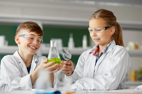 Niños con frasco y lupa en la clase de química — Foto de Stock