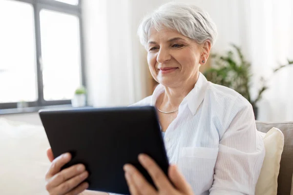 Felice donna anziana con tablet pc a casa — Foto Stock