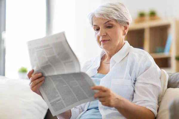 Senior woman reading newspaper at home — Stock Photo, Image