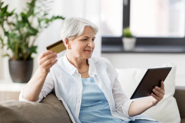 Mulher sênior com tablet pc e cartão de crédito — Fotografia de Stock