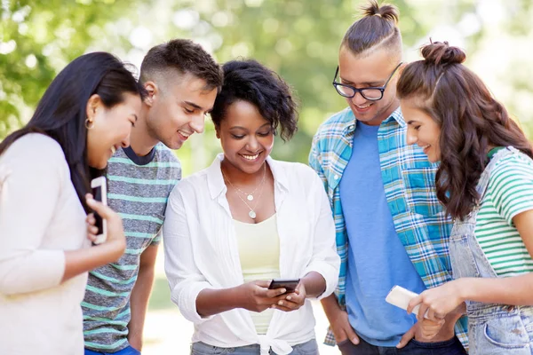 Groep gelukkige vrienden met smartphone outdoors — Stockfoto