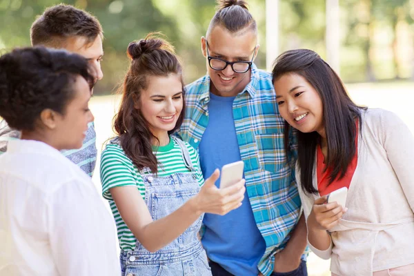 Groep gelukkige vrienden met smartphone outdoors — Stockfoto