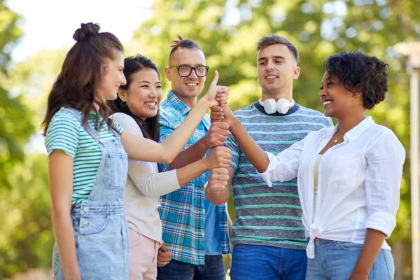 Feliz amigos haciendo pulgares hacia arriba gesto en el parque — Foto de Stock