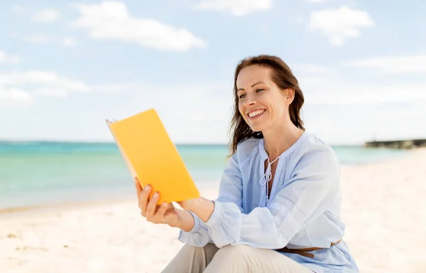 Glücklich lächelnde Frau liest Buch am Sommerstrand — Stockfoto