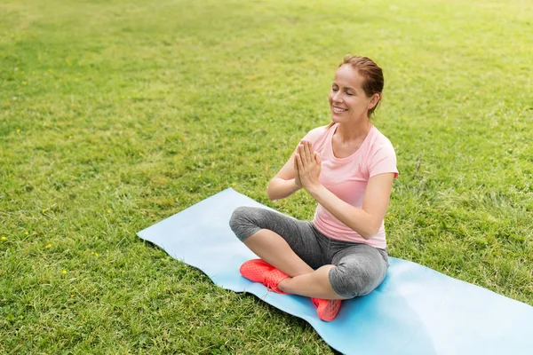 Lycklig kvinna mediterar i sommaren park — Stockfoto