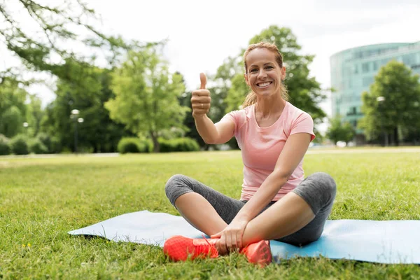 Femme sur tapis d'exercice au parc montrant pouces vers le haut — Photo