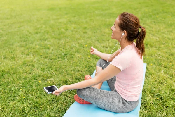 Kvinna som mediterar på yogamatta på park — Stockfoto