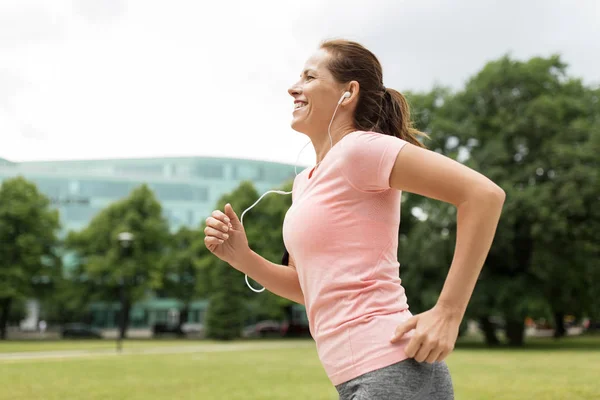 Woman with earphones running at park — Stock Photo, Image