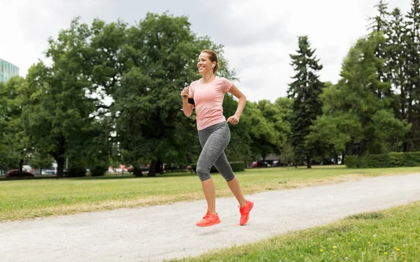 Mujer con auriculares corriendo en el parque — Foto de Stock