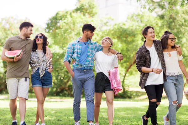 Amigos felizes com cobertor de piquenique no parque de verão — Fotografia de Stock