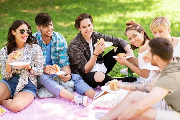 Happy přátelé jíst sendviče na letní piknik — Stock fotografie