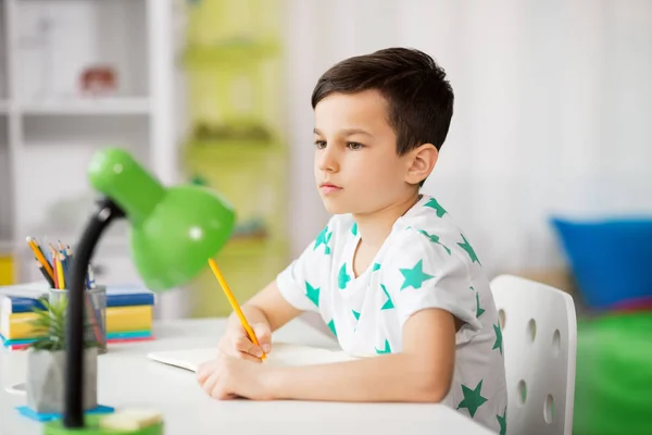 Mały chłopiec, w piśmie do notebooka w domu — Zdjęcie stockowe